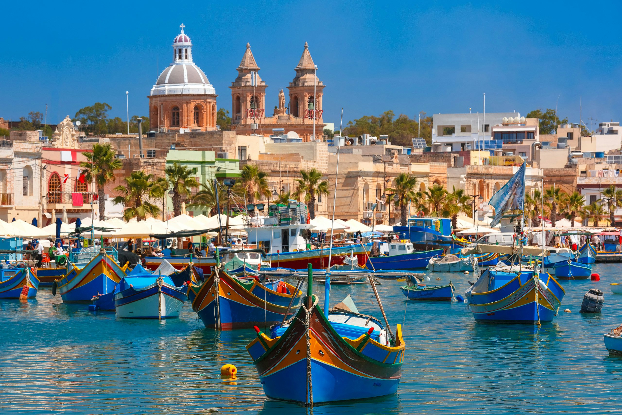 Colorful traditional fishing boats, or 'luzzus', in Marsaxlokk village, viewed from a yacht charter.