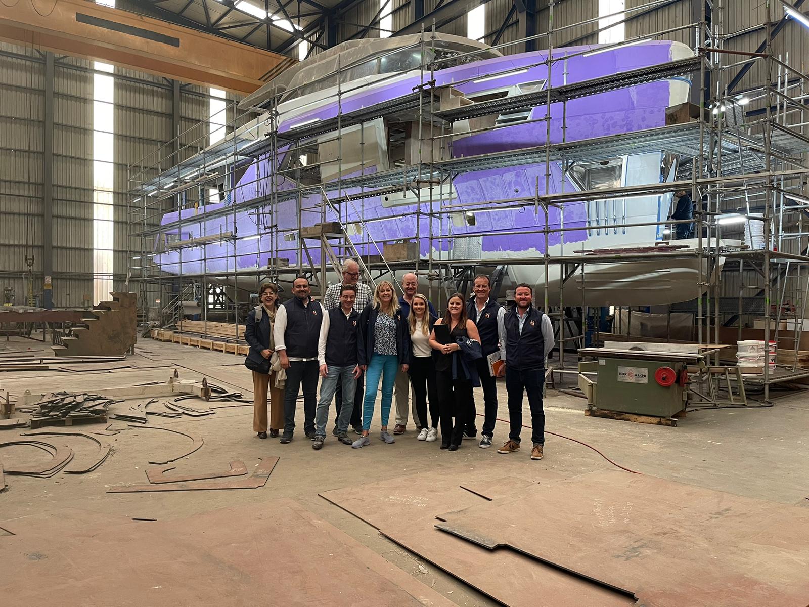 NJ brokers at a shipyard in turkey in front of a yacht under construction