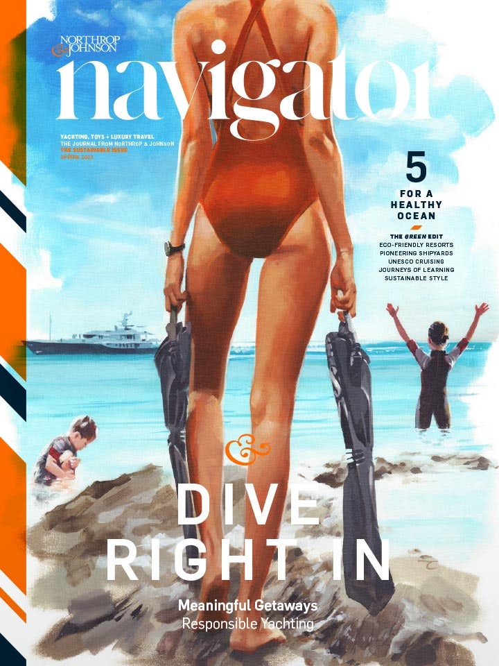 Woman at the water's edge with swimming fins in hand and kids playing in the water with superyacht in the horizon