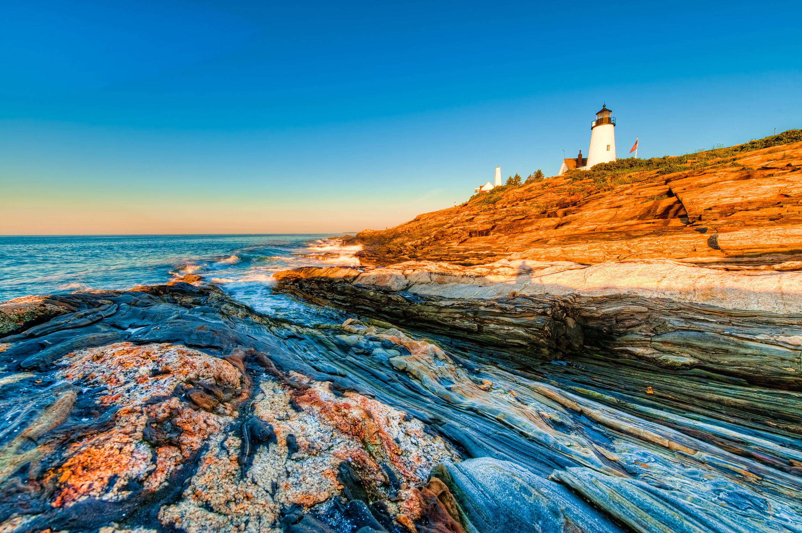 New England Yacht Charter - Lighthouse in New England with sunset ad rocky waters
