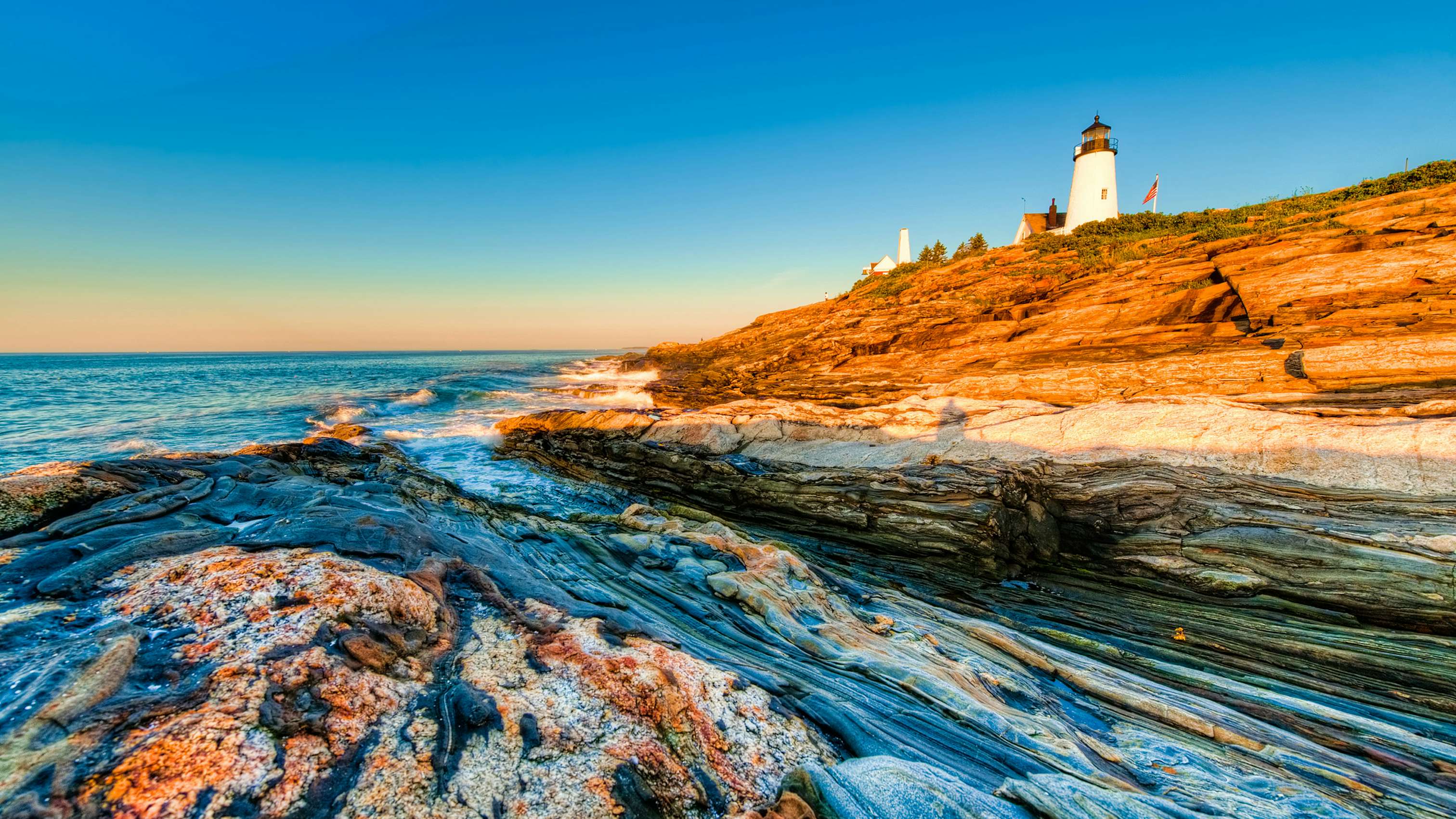 New England Yacht Charter - Lighthouse in New England with sunset ad rocky waters