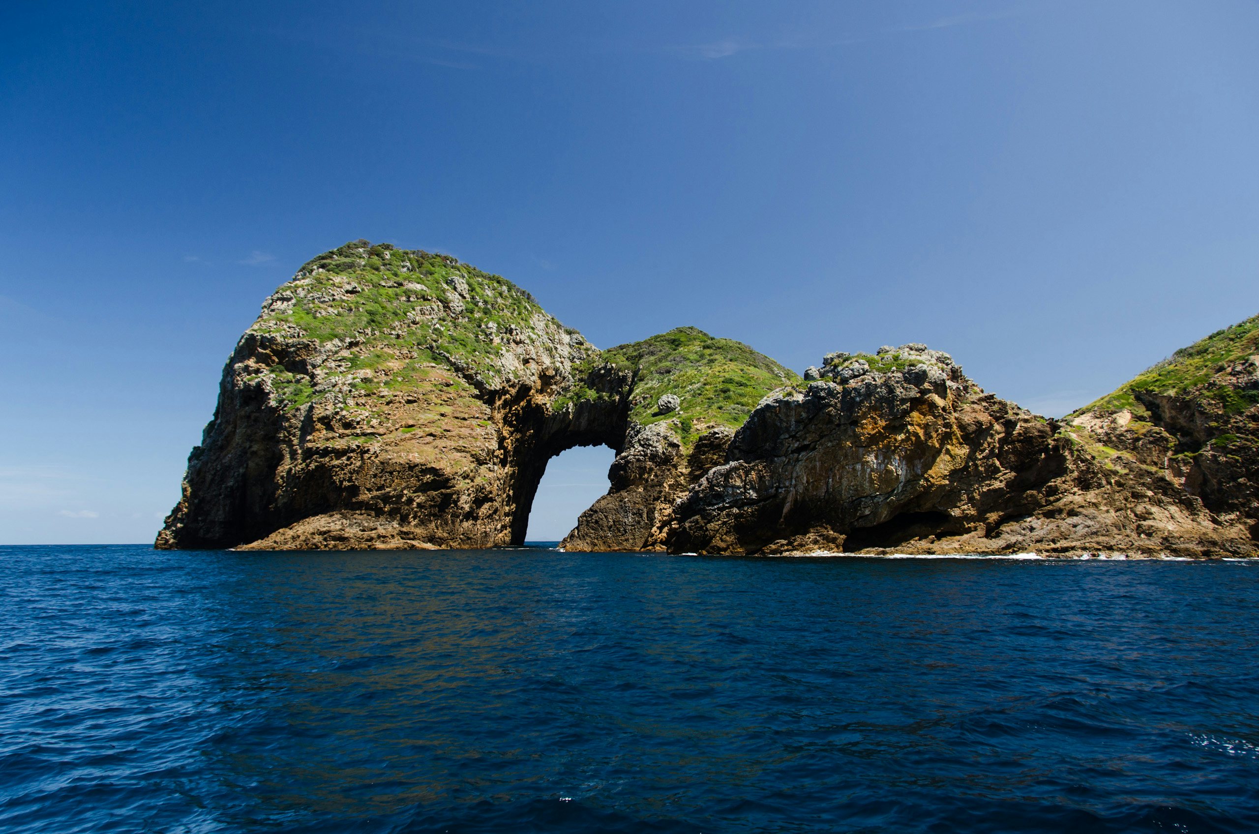 New Zealand Superyacht Charter - Rocks coming out of the water with a arch at Poor Knights Island, New Zealand