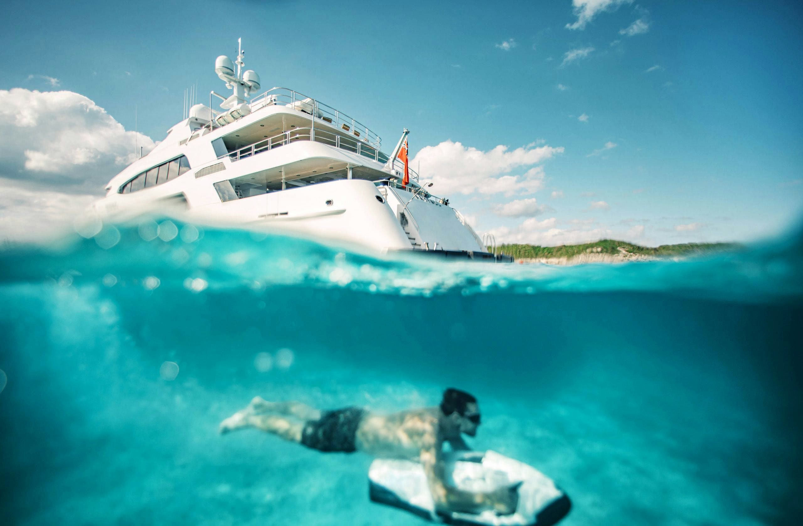 Guest diving under charter yacht SKYFALL with toy.