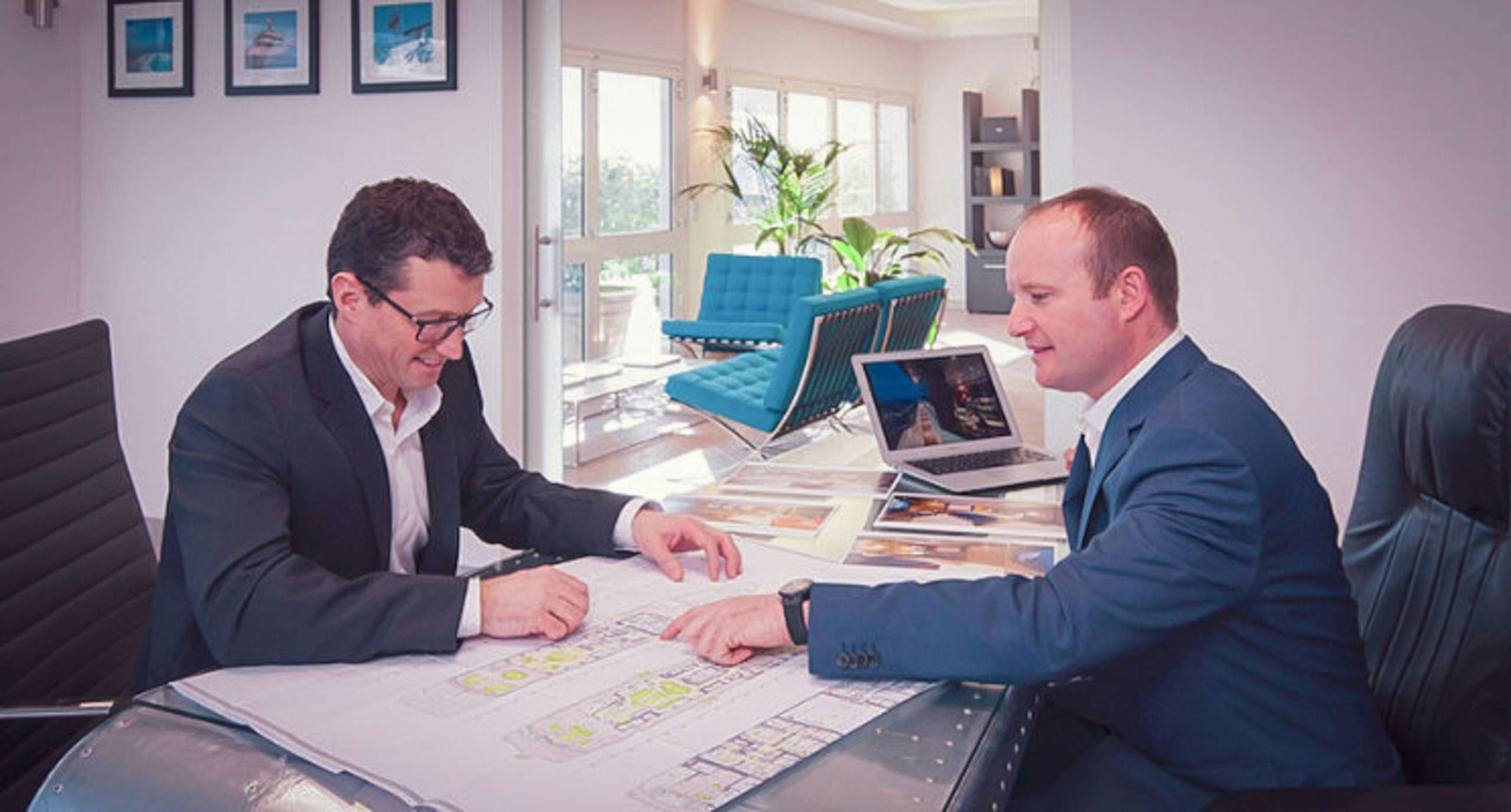 Yacht manager and client looking at yacht designs on desk
