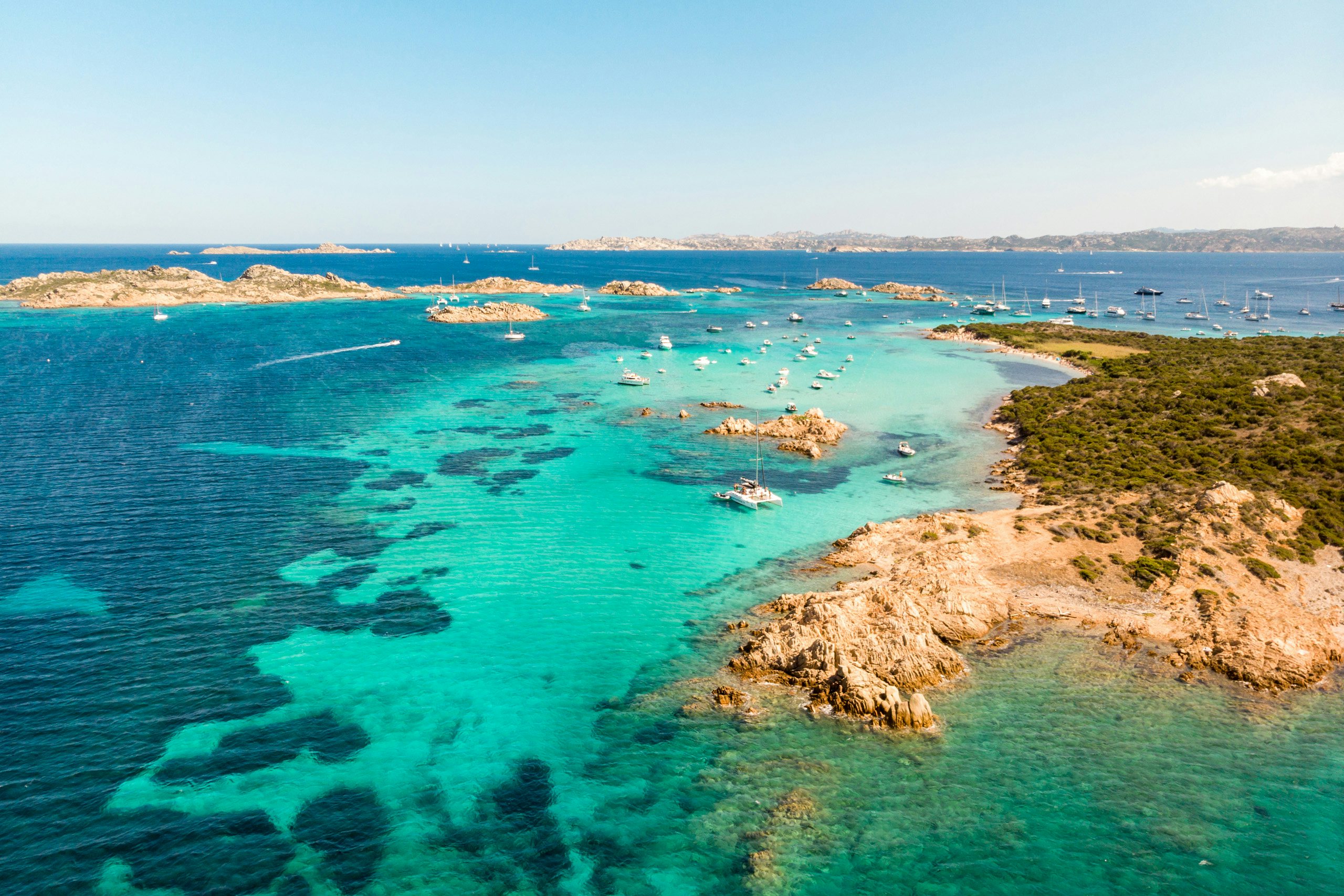 Sardinian Coastal Paradise - Explore with N&J Yachts Aerial view of crystal-clear turquoise waters surrounding the rugged coastline of Sardinia.