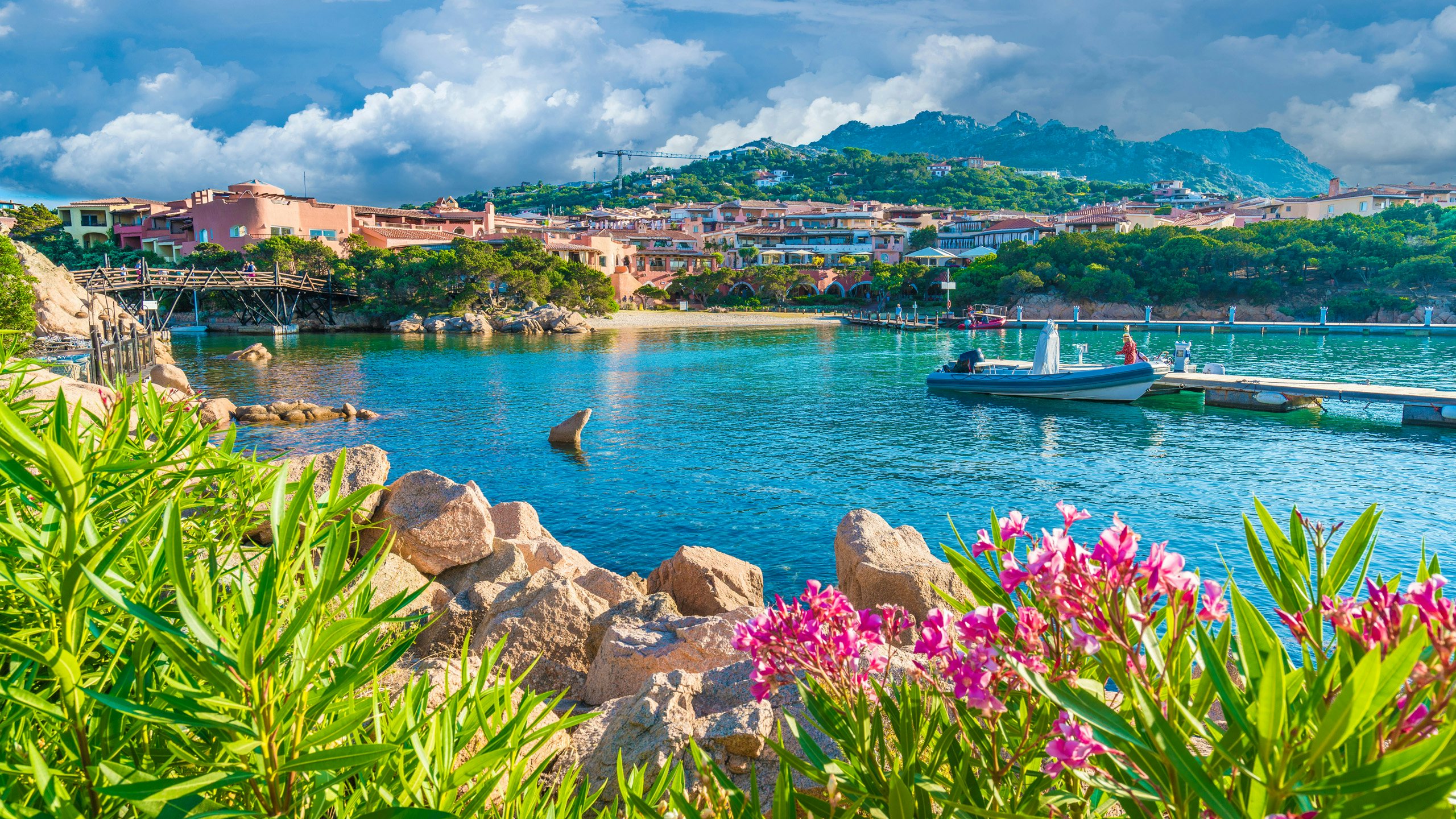 Sardinian Cove in Bloom - N&J Yacht Charter Retreat Vibrant flowers framing a serene Sardinian cove with yachts floating on calm waters.