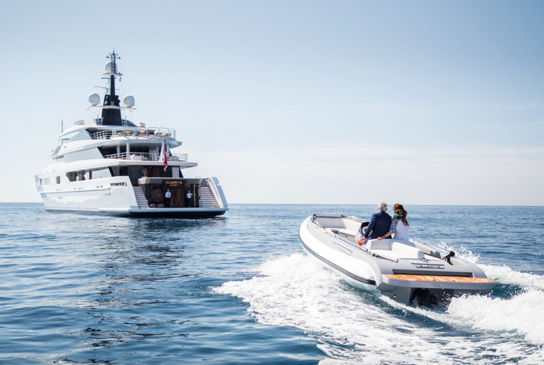 uhnw couple onboard luxury tender cruising to luxury superyacht at anchor in mediterranean sea