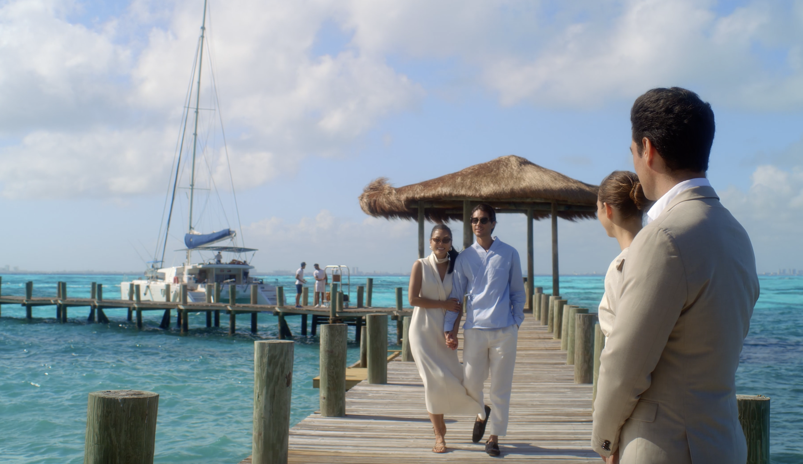 image of a couple arriving off a yacht somewhere tropical to two people in suits greeting them