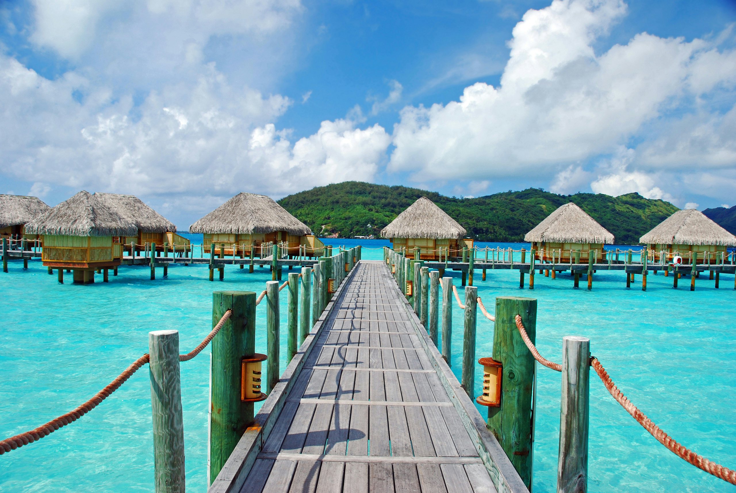 Society Islands Superyacht Charter - South Pacific_Bora Bora Society Islands Superyacht Charter - a dock in bora bora over beautiful blue waters leading to huts