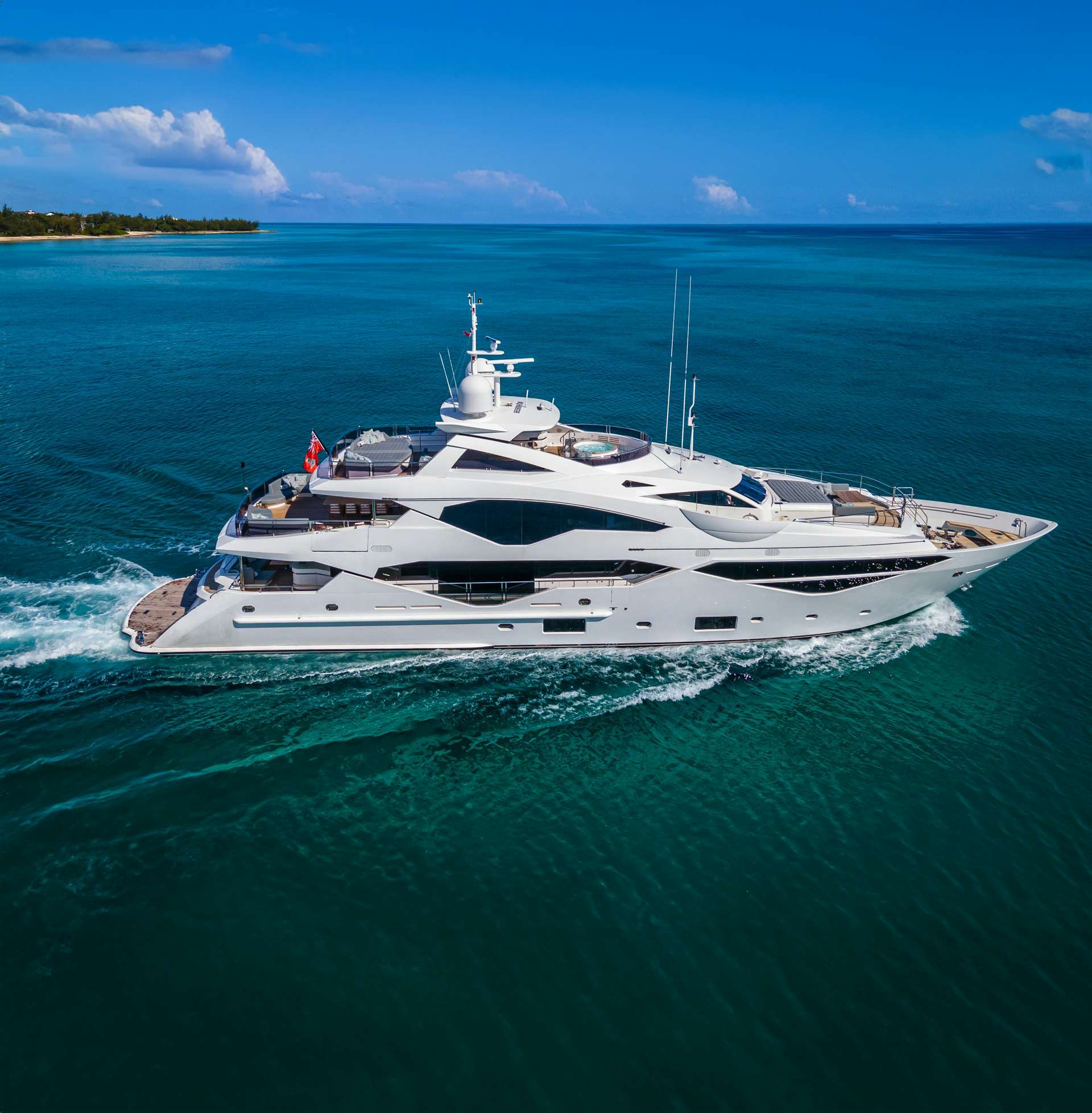 Aerial view of the Sunseeker 40 yacht sailing through turquoise waters, with a clear sky above and a hint of coastline in the distance.