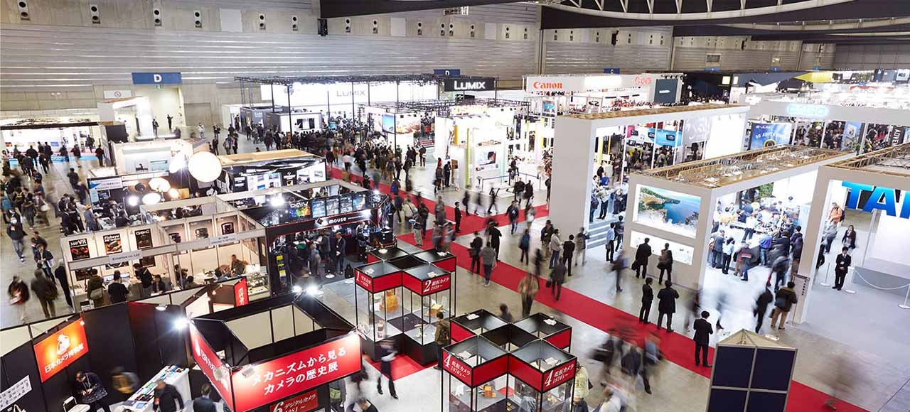 A convention hall with red carpet between stalls