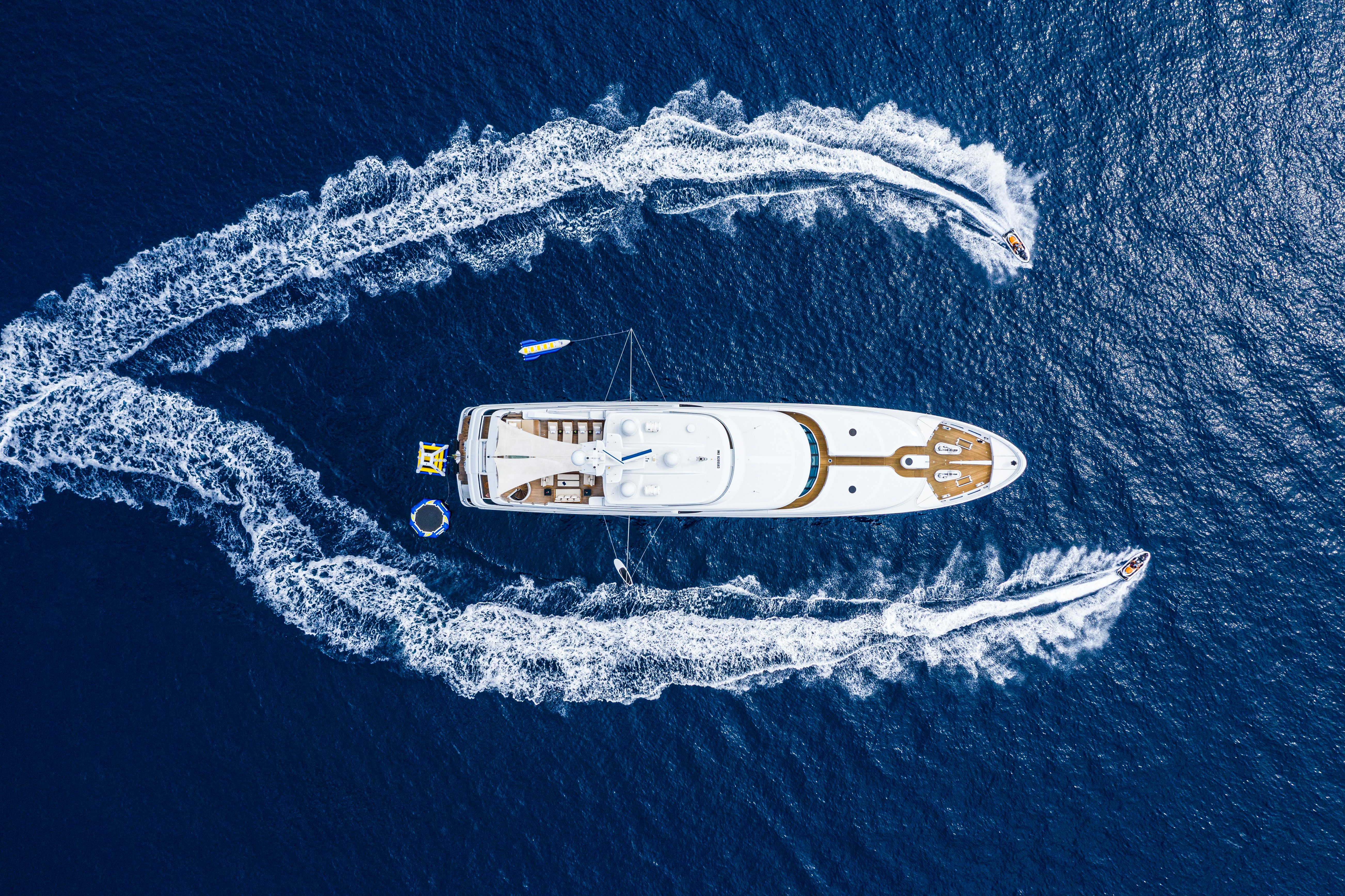 toys cruise around motor yacht victoria del mar while anchored in the blue ocean. the vantage point is from above