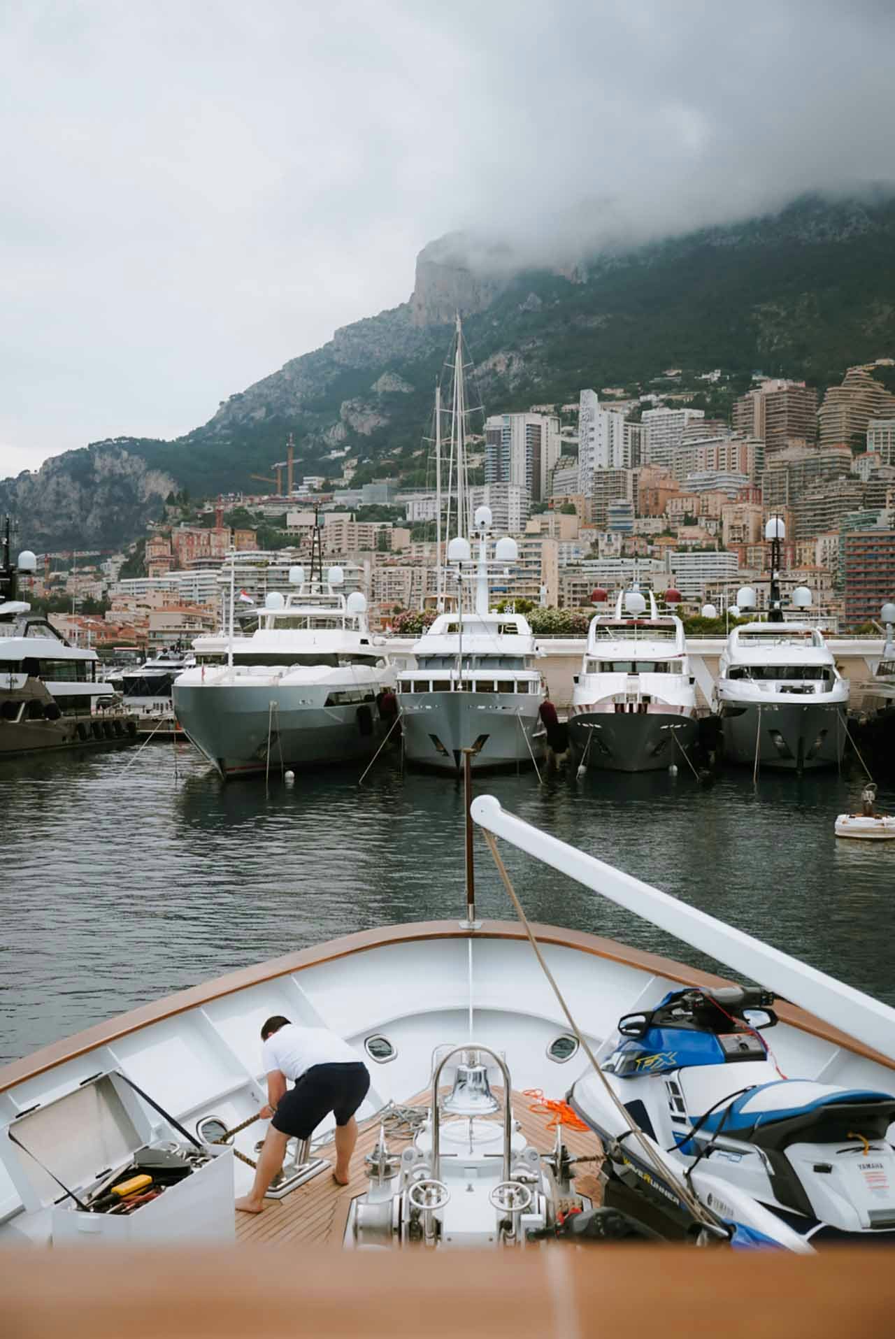 View over the bow of a superyacht with Monaco marina in the background