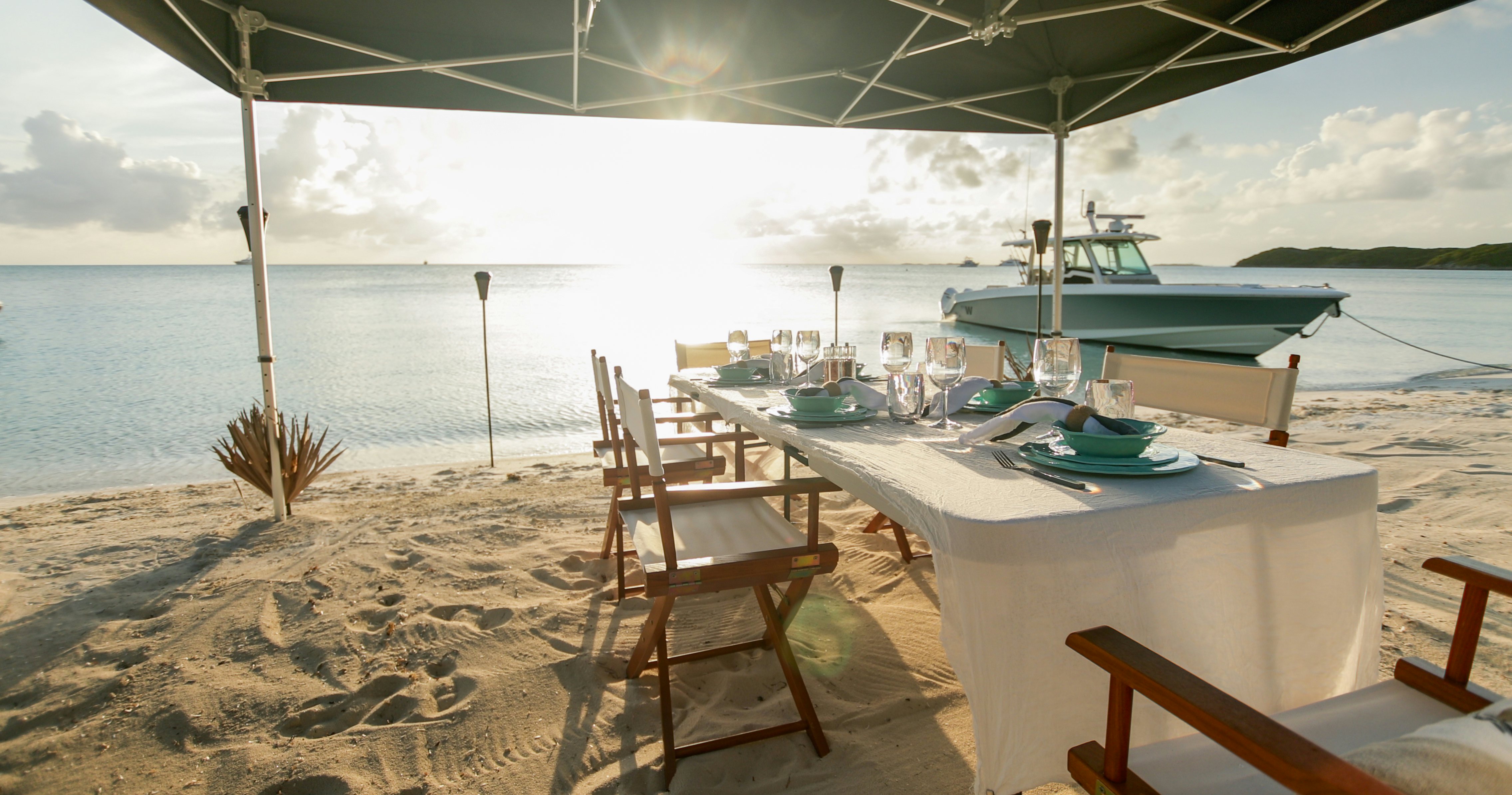 Beach set up for a meal with a yacht tender in the back of MY W