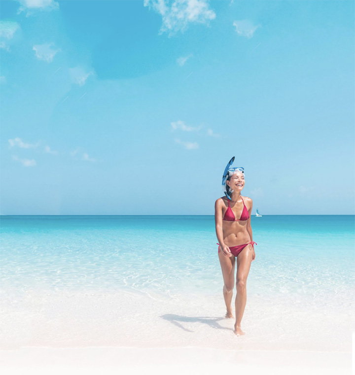 Woman walking on a tropical beach in a pink bikini