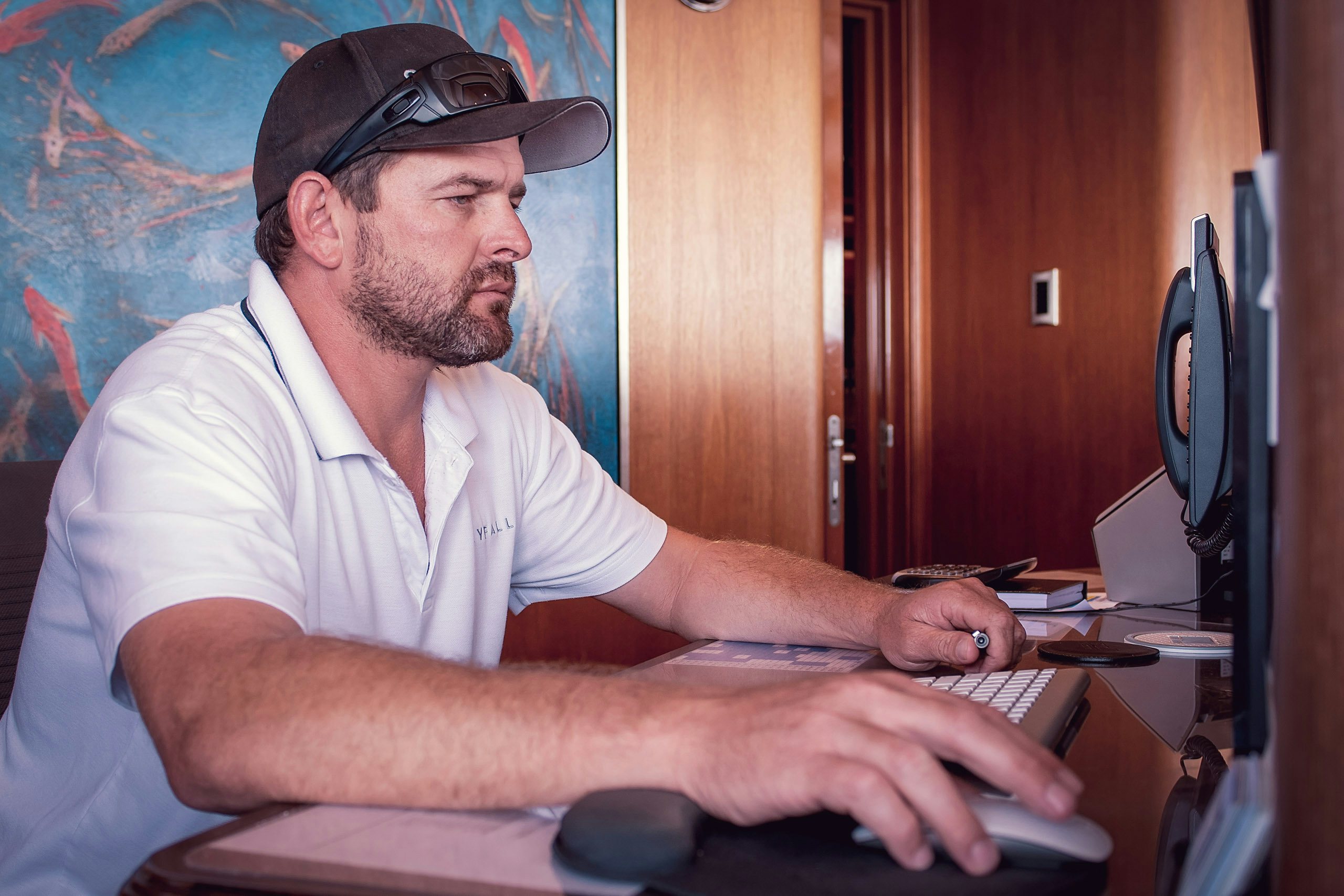 Yacht_Management-Registration_amd_regulation Senior crew member using computer on board superyacht