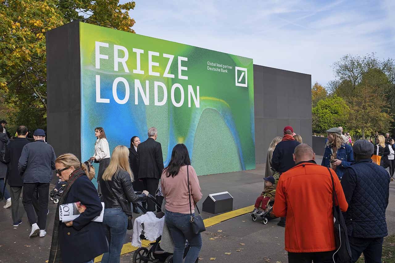 The entrance to Frieze London art fair with a large sign and a crowd of people