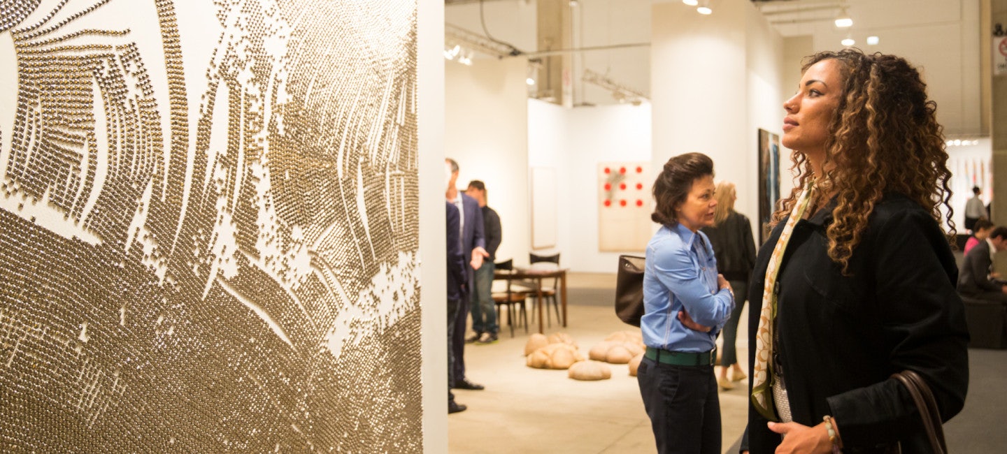 A young girl standing in wonder as she gazes at a captivating wall painting on display at Expo Chicago