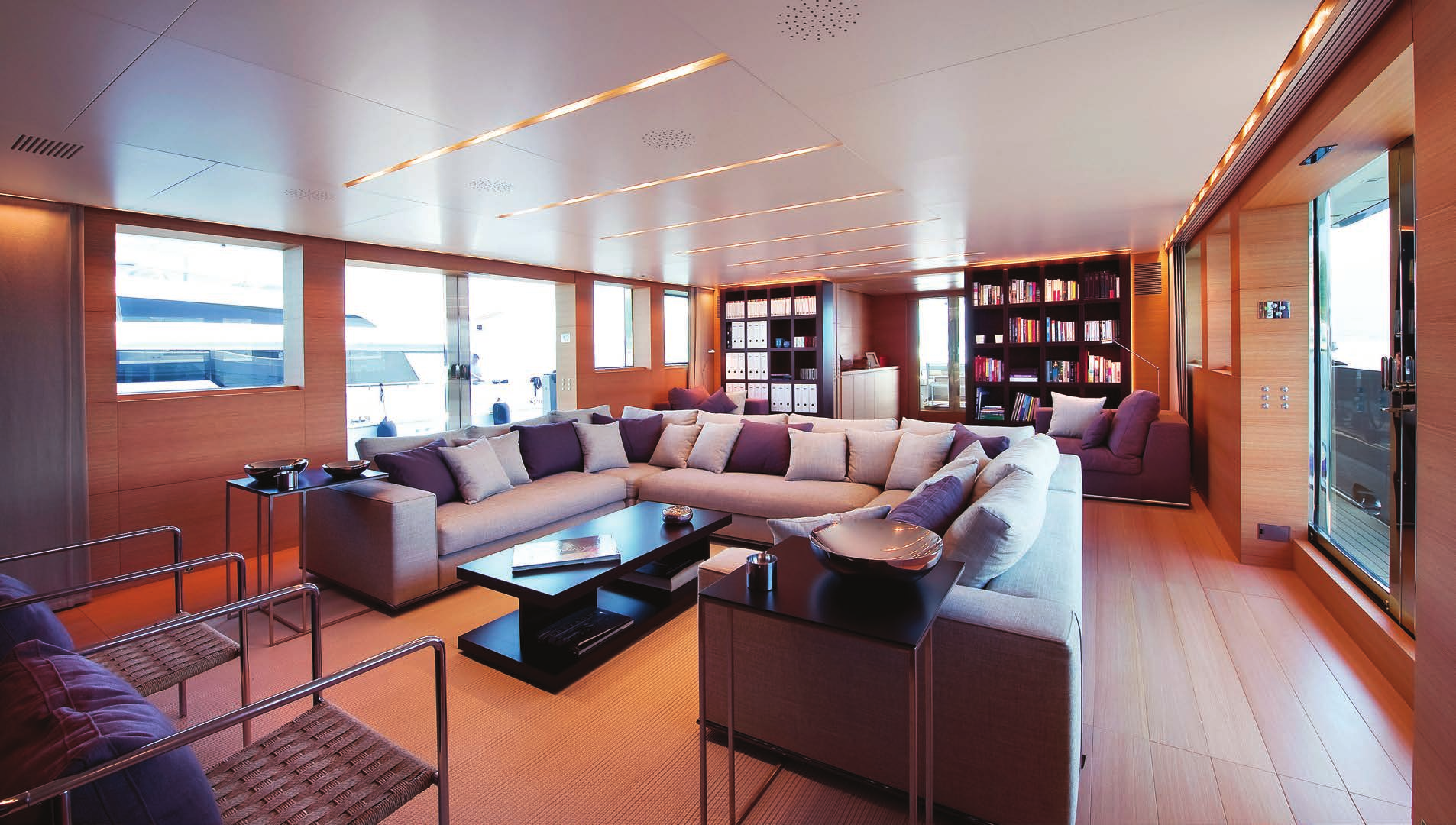 Main salon onboard the Sanlorenzo 40 Alloy yacht for sale by N&J, featuring a spacious L-shaped sofa, modern decor, and a bookshelf.