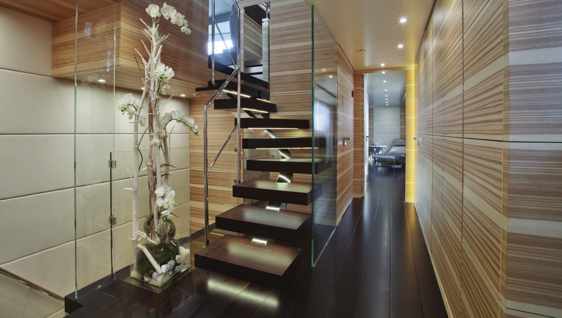 Elegant modern staircase in the entryway of the Sanlorenzo 40 Alloy yacht for sale with N&J, featuring atmospheric lighting and orchids.