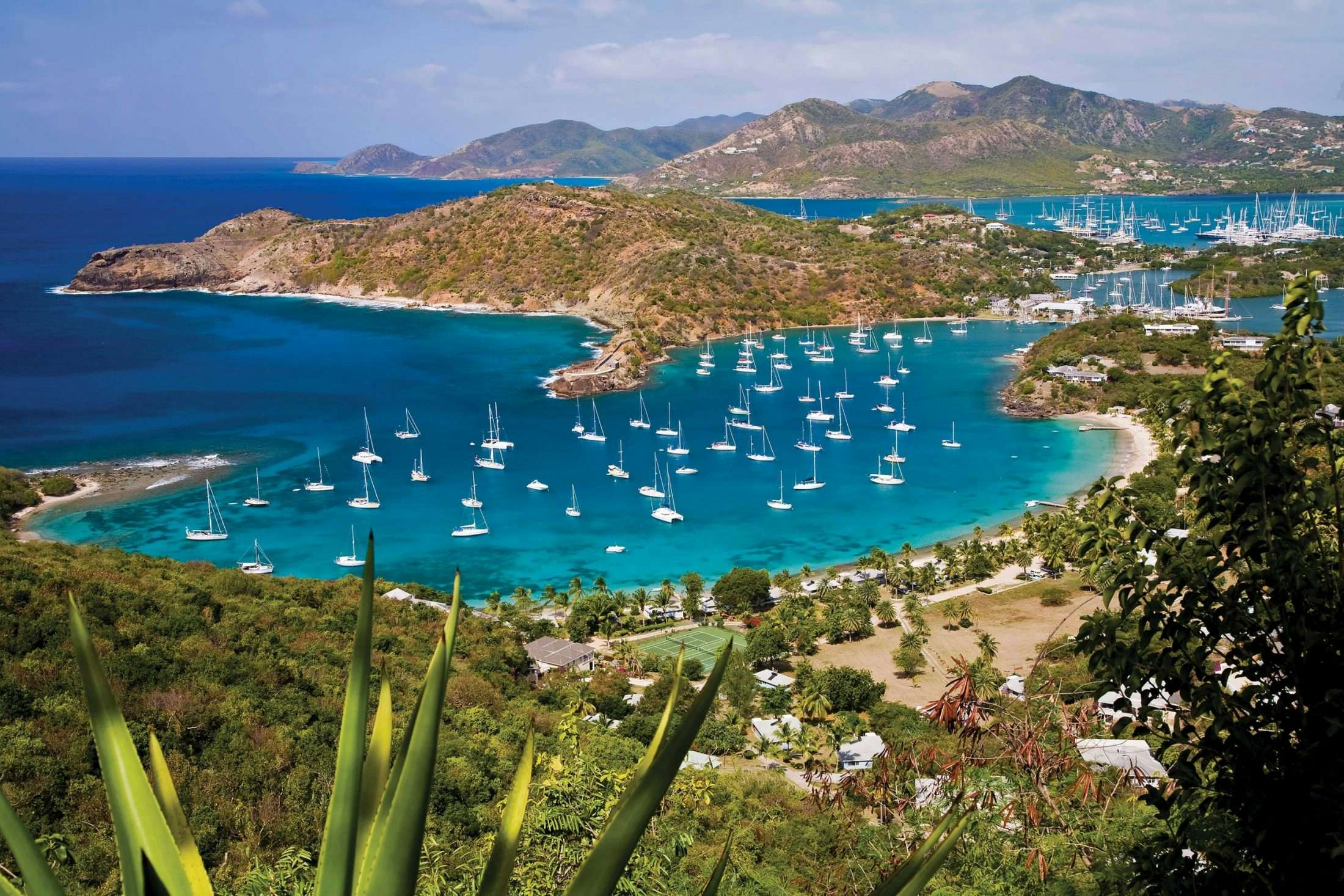 A stunning view from the top of Shirley Heights in Antigua, showcasing the vibrant harbor, anchored boats, and the sparkling sea—a captivating scene for your Antigua Yacht Experience.
