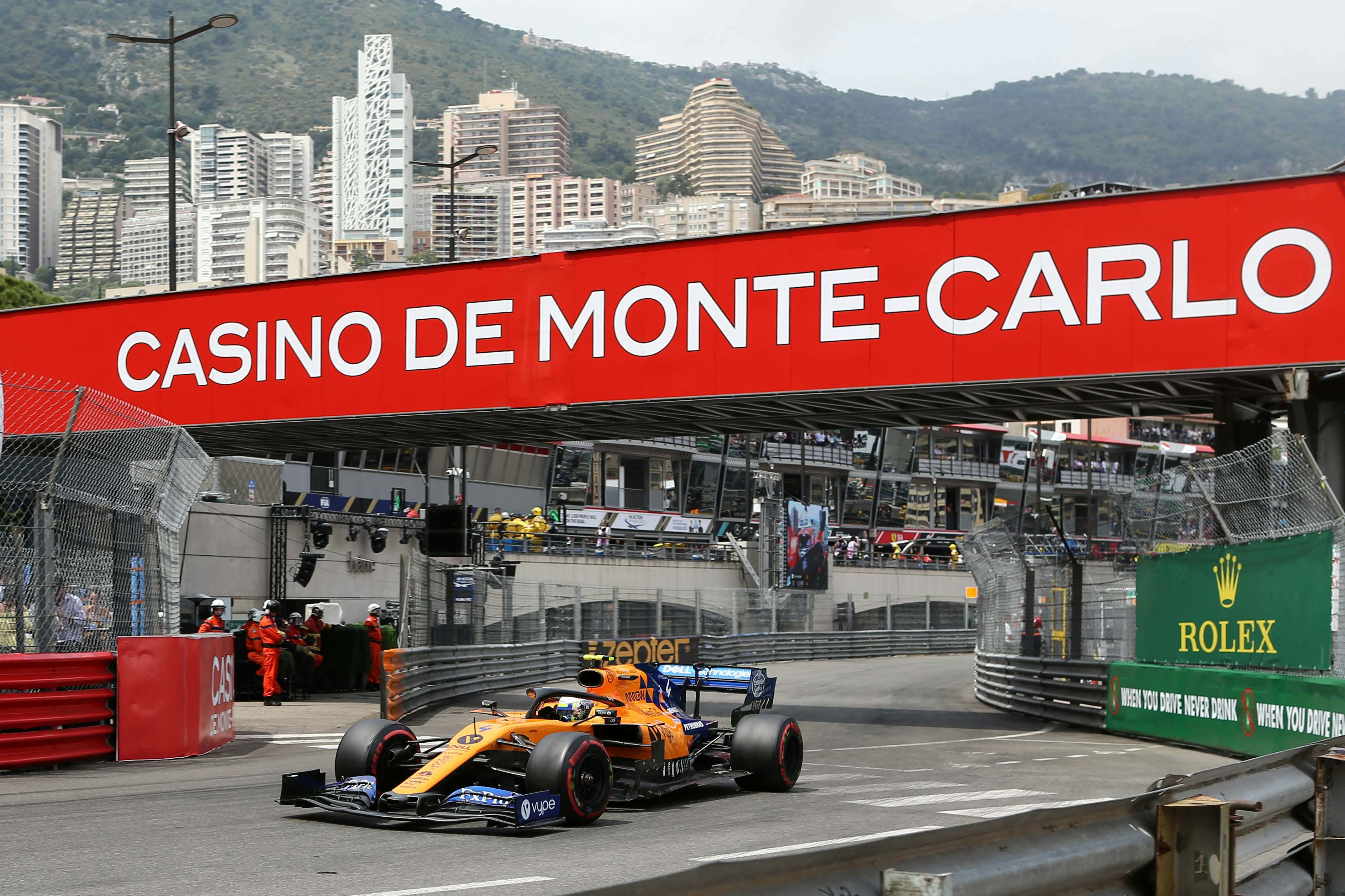 A Formula One car racing on the iconic Monaco track, with the stunning Monaco landscape in the backdrop, showcasing the perfect reason to charter a yacht for the Monaco Grand Prix.