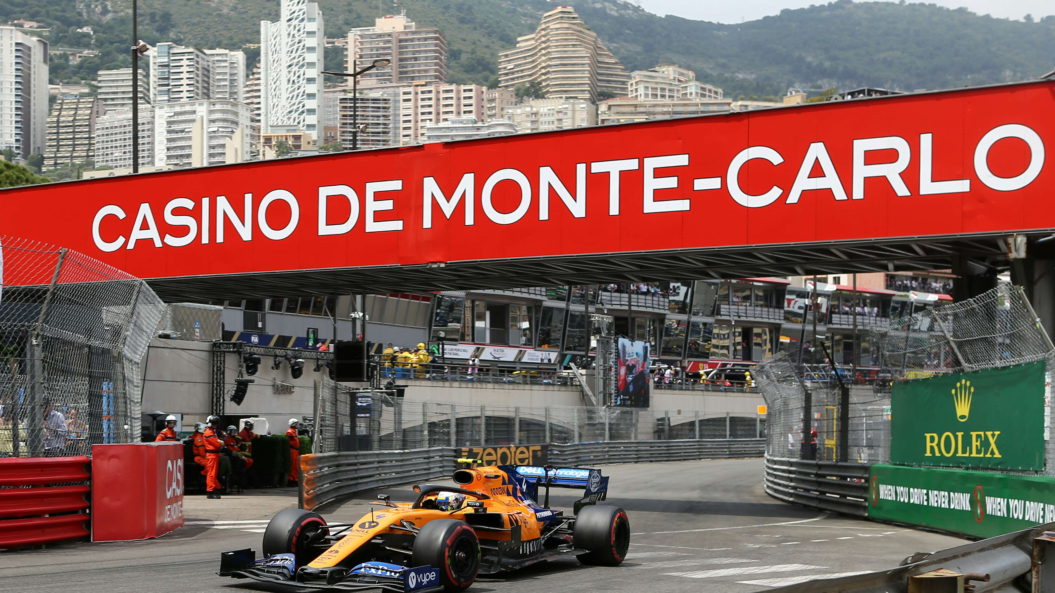 A Formula One car racing on the iconic Monaco track, with the stunning Monaco landscape in the backdrop, showcasing the perfect reason to charter a yacht for the Monaco Grand Prix.