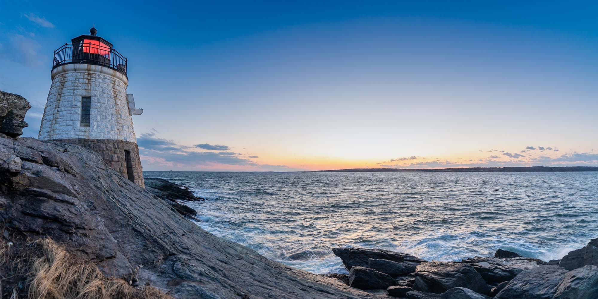 Spectacular Newport New England Sunset: Rocks, Cliffs, and Waves A breathtaking view of the rocky beach and dramatic cliffs along the coast of Newport, New England, as the waves crash under a fiery sunset sky.