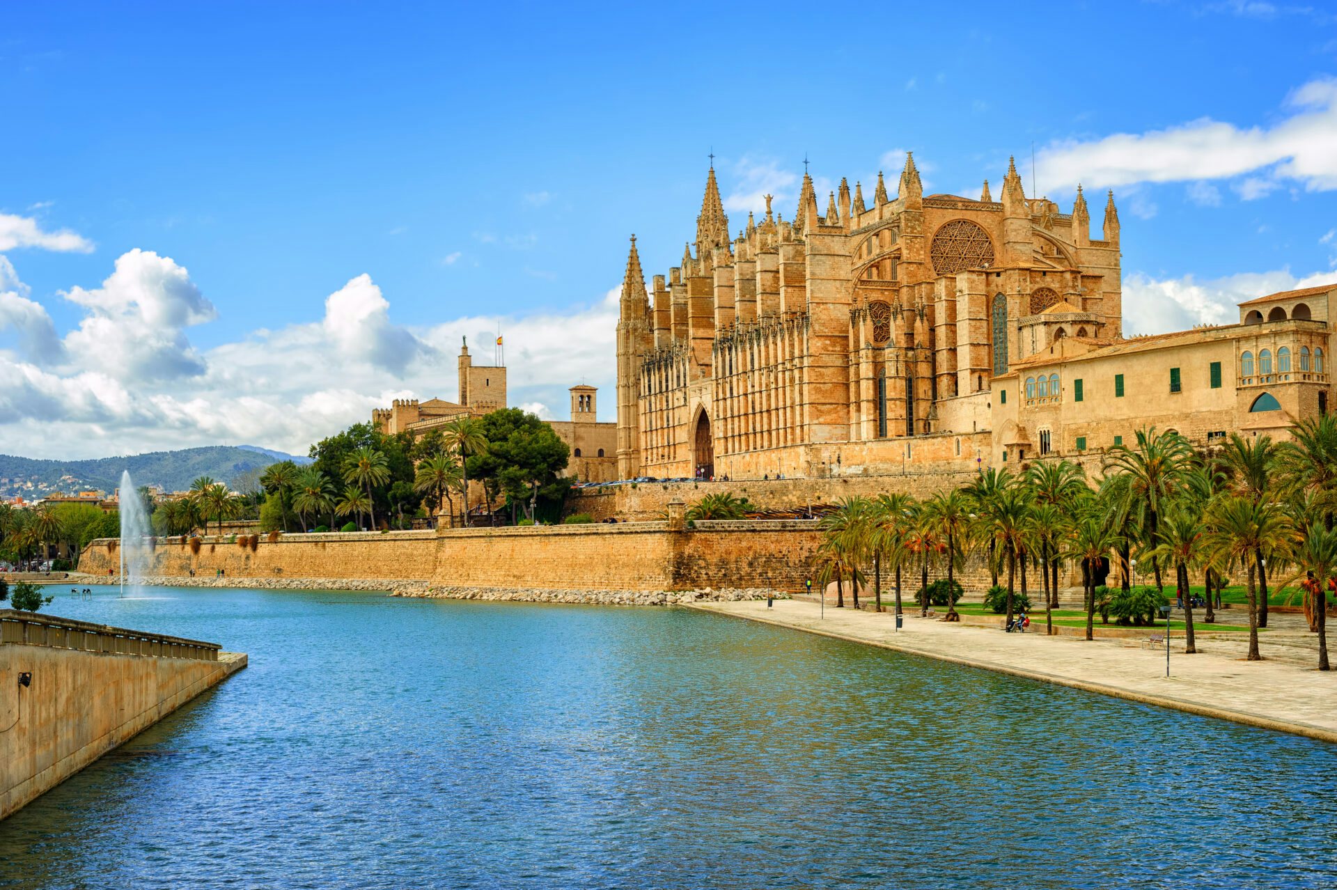 A picturesque side view of a castle in Palma de Mallorca, with the sparkling channel and clear blue skies on a sunny day
