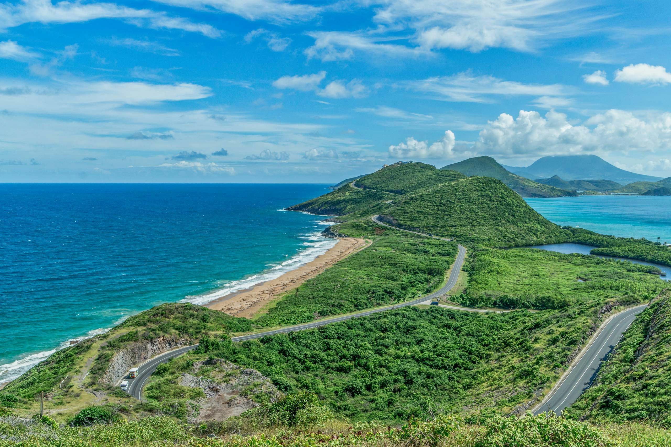 An awe-inspiring aerial shot of the roadways on St. Kitts, surrounded by mountains and vibrant lush greenery in the Caribbean Leeward Islands.