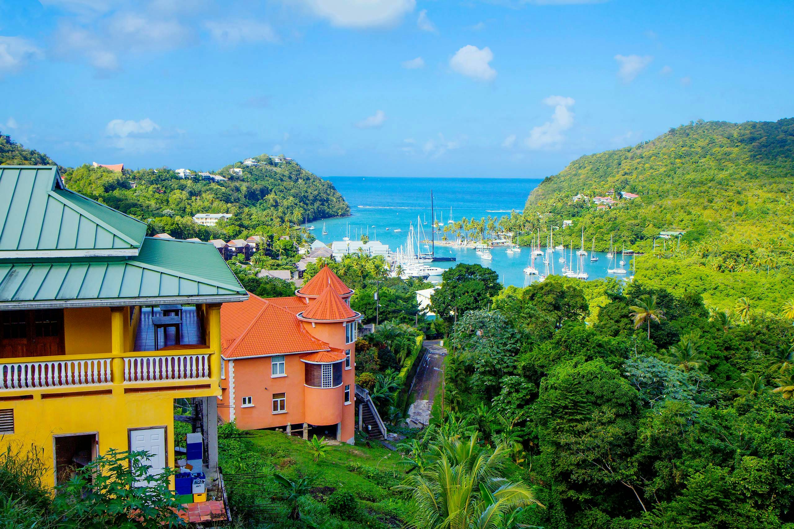 A picturesque view of beautiful, colorful buildings on the island of St. Lucia, with superyachts gracefully anchored in the background amidst the azure waters—a scene of Caribbean beauty for your St. Lucia Superyacht Charter.