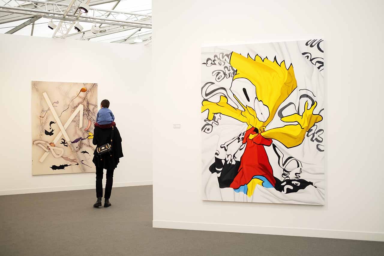 A single visitor stands among artworks in a gallery