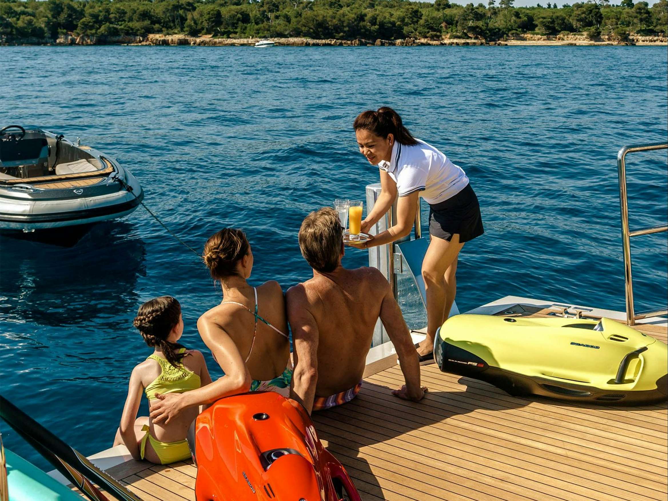 Luxury yacht charter, family being offered refreshments on lower deck