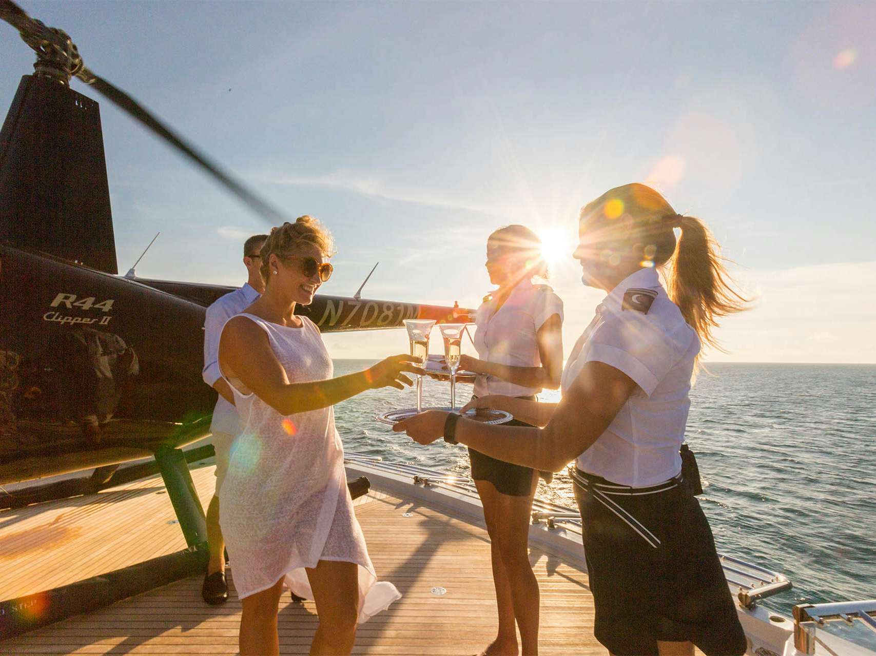 Couple being offered champagne after landing on superyacht via helicopter